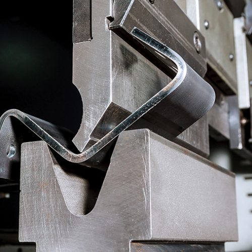 The process of bending sheet metal on a hydraulic bending machine. Metalworking plant.